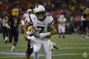 (Matthew Kawamoto | Trojan Times) Wide Receiver Bronson Ramos (12) catches a 15-yard pass and runs it all the way for a touchdown after breaking a tackle, scoring another six points for the Mililani Trojans. 